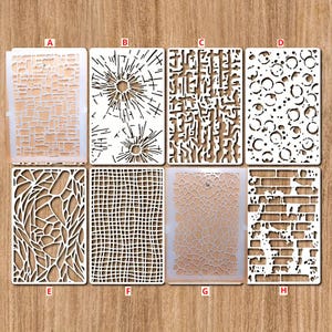 May include: Eight different stencils for crafting and decorating. The stencils are made of white plastic and feature various designs, including brick, cracked glass, and geometric patterns.