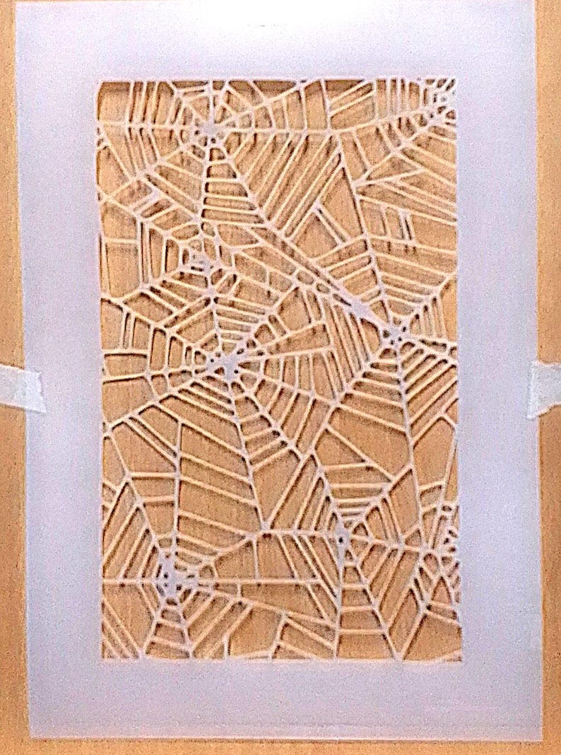 May include: A rectangular stencil featuring a repeating white spider web pattern on a translucent sheet. The design consists of multiple interconnected web centers with radiating lines and concentric segments, creating a detailed geometric network.