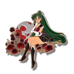 May include: Enamel pin featuring a seated anime-style character with long green hair, wearing a black and burgundy outfit. The character is set against a backdrop of a silver moon with red accents and surrounded by red flowers. The pin has gold-colored trim.