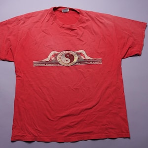May include: Red t-shirt with a graphic of a yin yang symbol and the text "Sunset Beach" and "Sunset Pipeline".