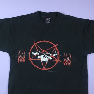 May include: Black t-shirt with a red pentagram and skull graphic. The graphic features a skull with horns and a pentagram inside a circle. The words "Blood Devil" are written on either side of the graphic.