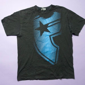 May include: A dark green t-shirt with a blue and white graphic of a star inside a stylized shape.
