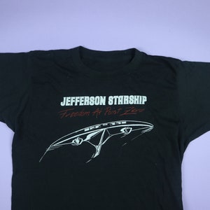 May include: Black t-shirt with a white graphic of a spaceship and the text "Jefferson Starship Freedom At Point Zero".
