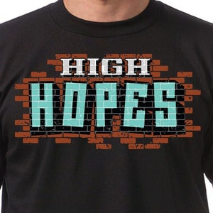 May include: Black t-shirt with a graphic of a brick wall with the words "HIGH HOPES" in blue.
