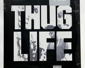 May include: Black and white album cover for the 25th anniversary of the album "Thug Life" by 2Pac. The album cover features a black and white photo of four men in front of a brick wall. The album cover also includes the text "25th Anniversary 180 Gram Vinyl" and "Parental Advisory Explicit Lyrics".