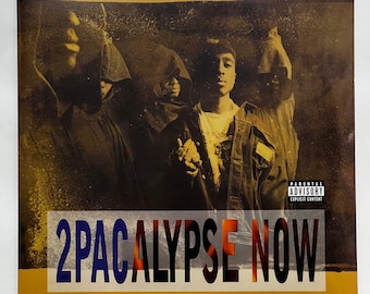 May include: A yellow and gold album cover with the text "2PACALYPS NOW" in blue and red letters. The cover features a group of people wearing dark clothing and a parental advisory sticker.