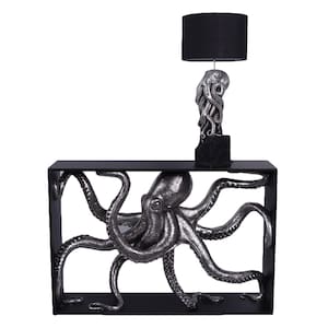 May include: A black rectangular console table featuring a large, silver-toned octopus sculpture integrated into its frame. A matching table lamp with a black cylindrical shade and a silver octopus-shaped base sits on the table surface.