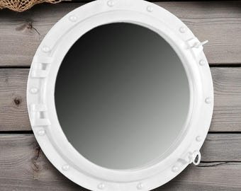 May include: A white, round porthole mirror with a nautical theme. The mirror has a white frame with rivets and a latch. The background is weathered wood. A fish net is in the upper left corner.