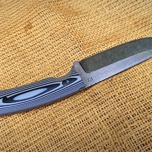 Op de afbeelding: Een mes met vast blad met een donker, getextureerd lemmet en een handvat met een zwart-wit gestreept patroon. Het mes heeft een full tang constructie en een gebogen lemmet. De handgreep is ergonomisch ontworpen voor een stevige grip. Het lemmet heeft de tekst "Z3".