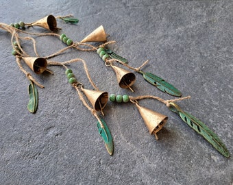 May include: A string of bells with green feathers and beads. The bells are gold and the feathers are a dark green color. The beads are a light green color.