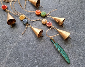 Windchime with cow bells on a string with round ceramic beads and a green patina brass feather pendant, witch bells, door hanger, suncatcher
