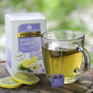 May include: Three boxes of Twinings Inner Strength, Inner Clarity, and Inner Peace herbal tea. Each box features a different blend of herbs and spices, including cinnamon, honey, lemon, chamomile, fig, and vanilla. The boxes are displayed on a wooden surface with a cup of tea in front of each box.