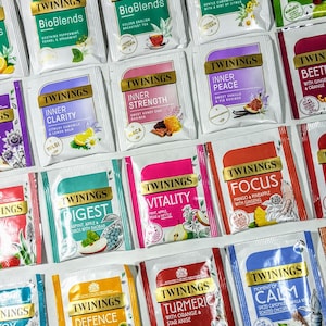 May include: A collection of 16 different Twinings tea boxes with various flavors, including Sleep, Inner Clarity, Inner Strength, Inner Peace, Beetroot with Ginger & Orange, Digest, Vitality, Focus, Heart, Defence, Turmeric with Orange & Star Anise, Moment of Calm, and Glow. The boxes are arranged in a grid pattern on a white surface.