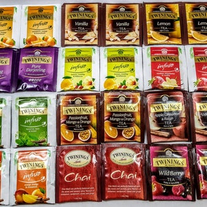 May include: A collection of 18 individually wrapped tea bags from the brand Twinings. The tea bags are arranged in a grid pattern and feature a variety of flavours, including Darjeeling, Vanilla, Lemon, Passionfruit, Mango & Orange, Apple, Cinnamon & Raisin, Chai, and Wild Berry.
