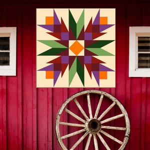 May include: A barn quilt with a starburst design in shades of green, purple, orange, and brown on a cream background. The quilt is hanging on a red barn.