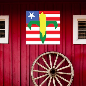 May include: A red barn with a white wagon wheel in front of it. A flag with a corn stalk design is hanging on the side of the barn.