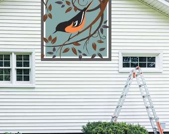 May include: A white house with a brown and orange bird on a branch in a blue and brown frame on the exterior wall. A ladder is leaning against the house.