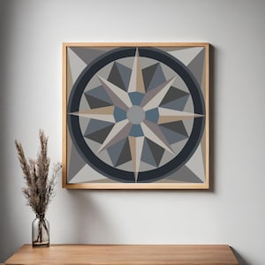 May include: A framed geometric art print with a starburst design in shades of gray, blue, and beige. The starburst is centered in the frame and has a circular border.