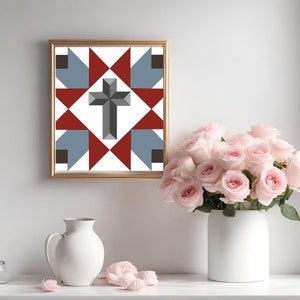 May include: A framed print of a quilt block with a red, white, and blue geometric pattern featuring a gray cross in the center.