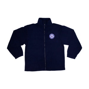 May include: A navy blue fleece jacket with a zipper closure and a circular embroidered patch on the left chest. The patch features a white eagle with a red shield and the text "United States of America".