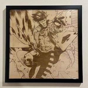 May include: A wood-burned illustration of a comic book character, Gambit, holding a playing card and a staff. The background is a wood-grain pattern with a dynamic, action-filled design.
