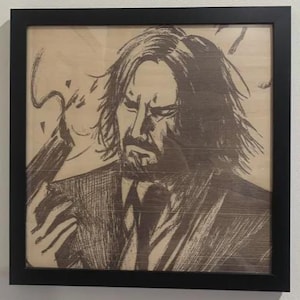 May include: A framed, sepia-toned sketch of a man with long hair, wearing a suit and tie. The artwork is in a black frame, and the drawing style is detailed with visible cross-hatching. The man's expression is intense.