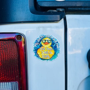 May include: A yellow rubber duck with sunglasses is on a sticker that says "My ducks were in a row... But then I hit a curb."