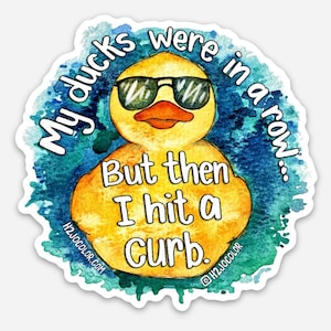 May include: A yellow rubber duck wearing sunglasses with the text "My ducks were in a row... But then I hit a curb." on a blue watercolor background.