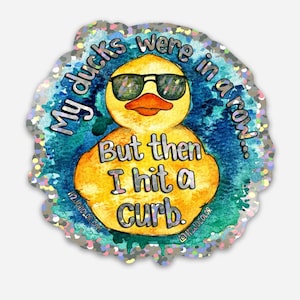 May include: A yellow rubber duck wearing sunglasses with the text "My ducks were in a row... But then I hit a curb."  The duck is on a blue and white background with a silver glitter border.