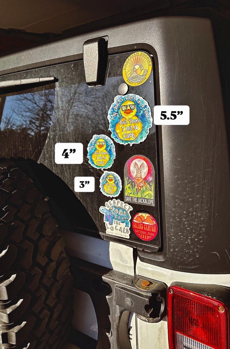 May include: A black Jeep with a variety of stickers on the back window. The stickers are different sizes and feature a variety of designs, including a duck, a jackalope, a turtle, and a mountain range. The stickers are 3 inches, 4 inches, and 5.5 inches in size.
