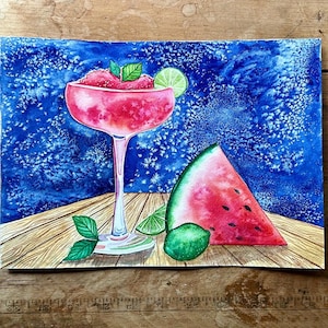 Pode incluir: Pintura em aquarela de um coquetel rosa congelado em um copo com haste, enfeitado com hortelã e limão. Uma fatia de melancia e fatias de limão estão ao lado do copo em uma superfície de madeira, em um fundo azul.