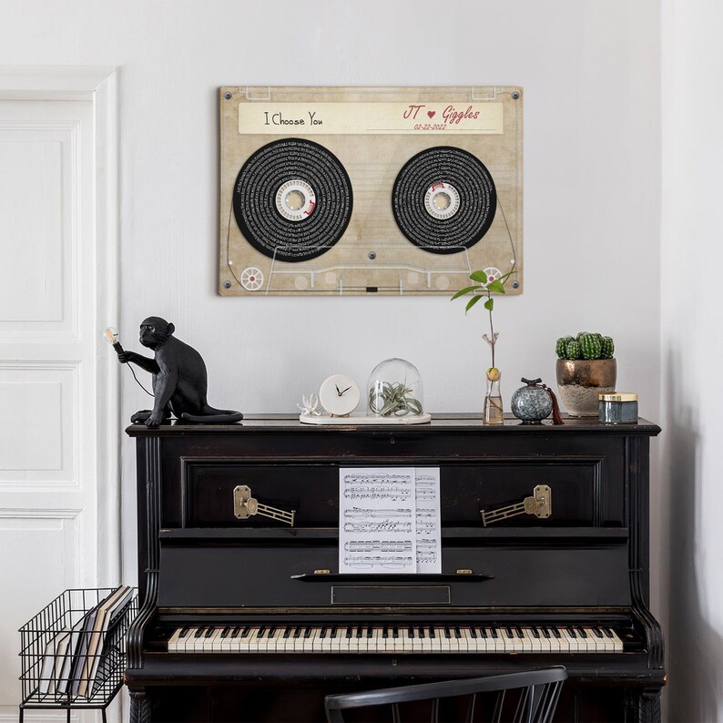 May include: A framed cassette tape design with the words "I Choose You" and "JT &hearts; Giggles 02-22-2022". The artwork features two circular tape reels with text. The artwork is displayed above a black piano with decorative items.