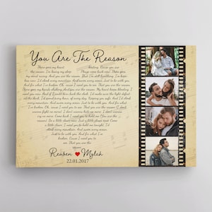 May include: A vintage-style canvas print with a love song lyric about a couple's relationship. The lyrics are printed on a background of musical notes and a film strip with four photos of a couple. The text reads "You Are The Reason" and includes the names Reuben and Mylah with the date 22.01.2017.
