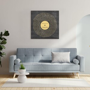 May include: A framed wall art piece featuring a vinyl record design. The record is centered on a dark gray background, with the lyrics of a song forming a circular pattern. The record label is gold with the text "Record with title" and names.
