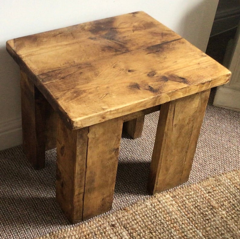 May include: A rustic wooden side table with a square top and four legs. The table is made of reclaimed wood and has a natural, weathered finish.