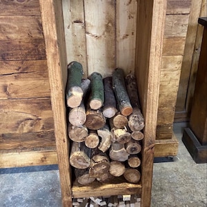 May include: A wooden log rack with two shelves. The top shelf is filled with logs and the bottom shelf is filled with kindling. The rack is on wheels and has a rustic brown finish.