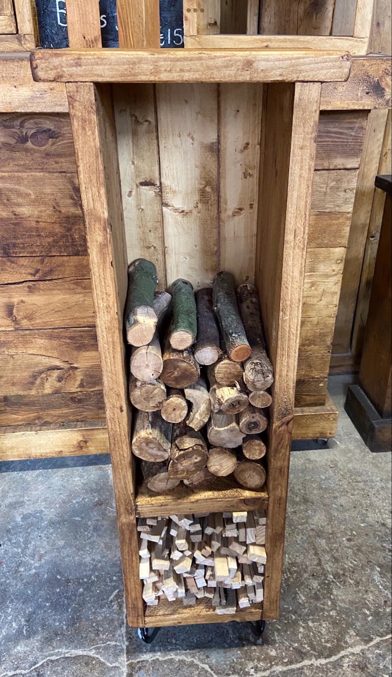 May include: A wooden log rack with two shelves. The top shelf is filled with logs and the bottom shelf is filled with kindling. The rack is on wheels and has a rustic brown finish.