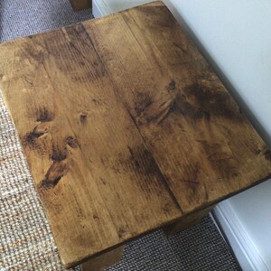 May include: A rustic wooden side table with a natural wood finish. The table has a rectangular top and a simple design.