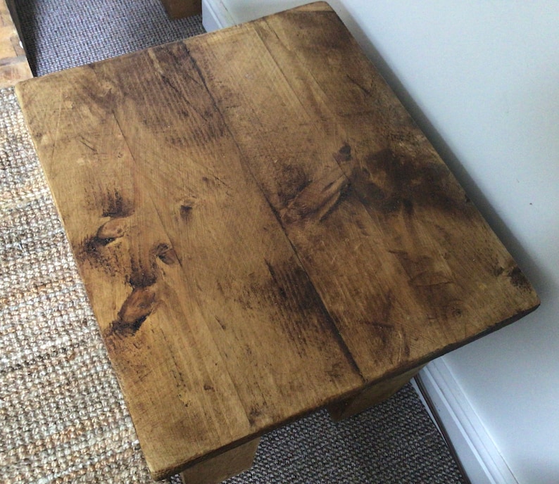 May include: A rustic wooden side table with a natural wood finish. The table has a rectangular top and a simple design.