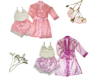 Puede incluir: Dos conjuntos de pijamas a rayas rosa y blancas con batas a juego. Un conjunto tiene una bata rosa y el otro una bata morada. Ambos conjuntos incluyen una parte superior de encaje y pantalones cortos.