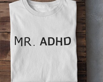 Peut inclure: T-shirt blanc avec le texte "MR. ADHD" imprimé en noir sur le devant.