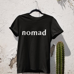 May include: Black t-shirt with the word "nomad" printed in white on the front.