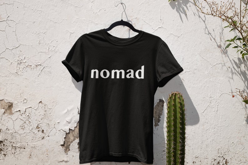 May include: Black t-shirt with the word "nomad" printed in white on the front.