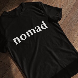 May include: Black t-shirt with the word "nomad" printed in white on the front.