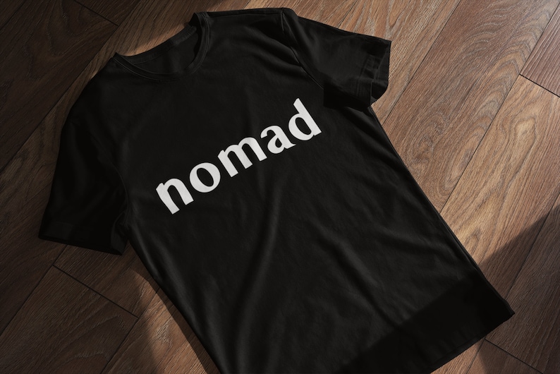 May include: Black t-shirt with the word "nomad" printed in white on the front.