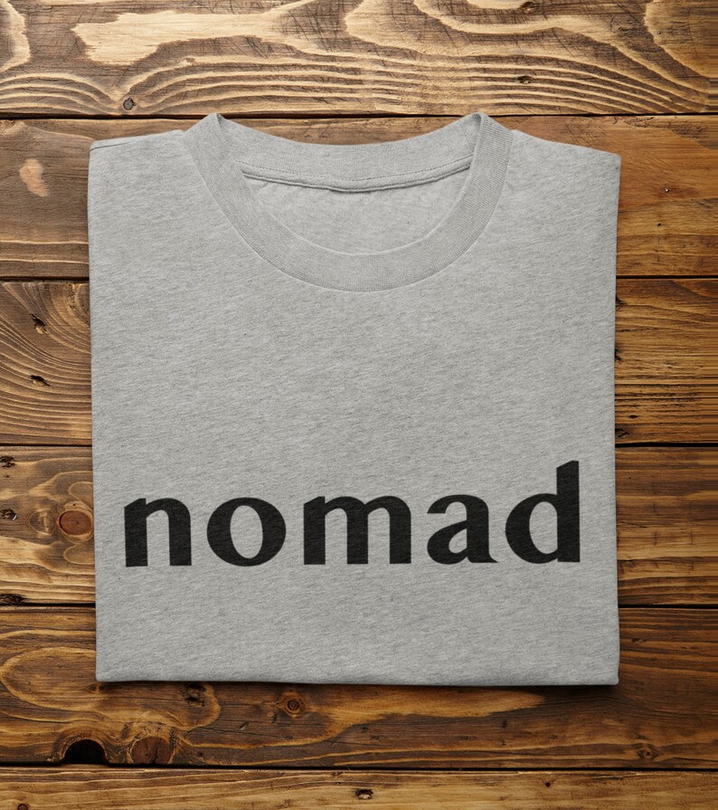 May include: A gray t-shirt with the word "nomad" printed in black on the front.