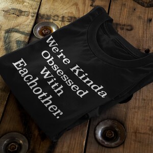 May include: Black t-shirt with white text that reads "Kinda Obsessed With Eachother."
