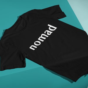 May include: Black t-shirt with the word "nomad" printed in white on the front.