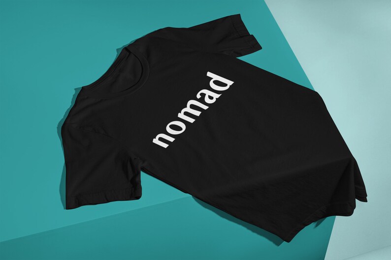 May include: Black t-shirt with the word "nomad" printed in white on the front.
