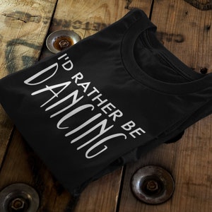 May include: Black t-shirt with white text that reads "I'd rather be dancing".